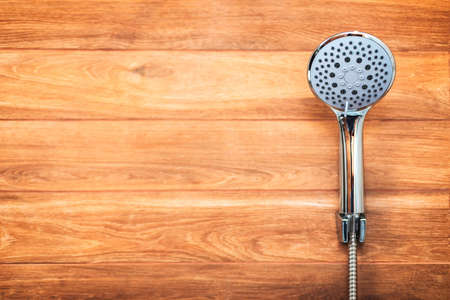 Hygiene concept. New shower head on the wooden wall backgroundの写真素材