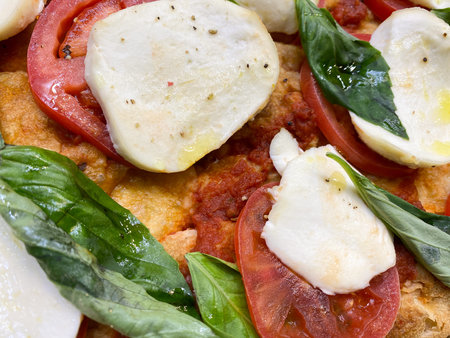 Italian fast food. Delicious hot pizza sliced and served on wooden platter with ingredients, close...