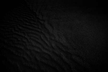 Black and White Sand beach macro photography. Texture of black and whote sand for background. Close-up macro view of volcanic sand surface black and white color. Black and white poster texture sand in the desert.の写真素材