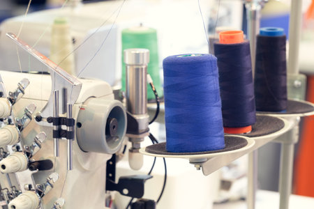 Reels of textile yarn blue thread at industrial weaving manufacturing machine