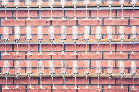 wine glasses in shelf above a bar rack in restaurant on a vintage brick wallの写真素材