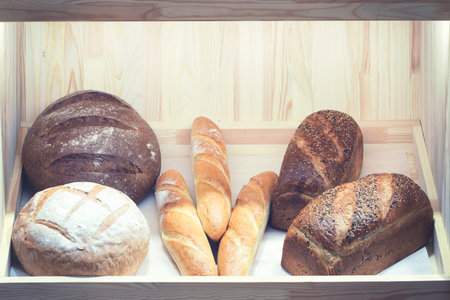 Lots of black and white bread on the store or bakery.