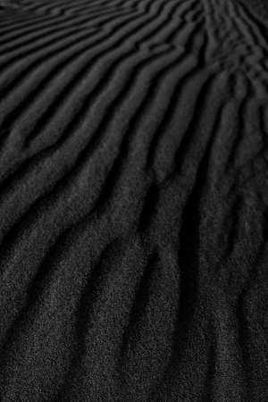 Black Sand dune. Black Sand beach macro photography. Background, texture, wave pattern of oceanic sand on the beach, black. Texture of beach sand. Black beach.の写真素材
