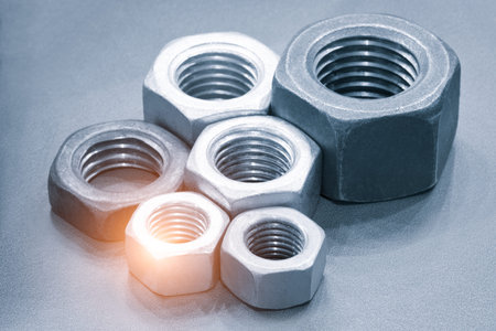 Metal nuts in a row. Chromed screw nuts. Tools for work.