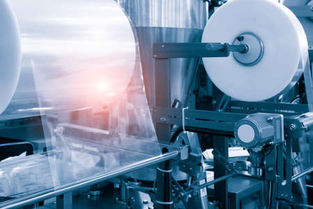 The operation of automatic plastic bag production machine with lighting effect. Close-up of the roller of the plastic bag production machine in the light blue scene. product packaging conceptの写真素材