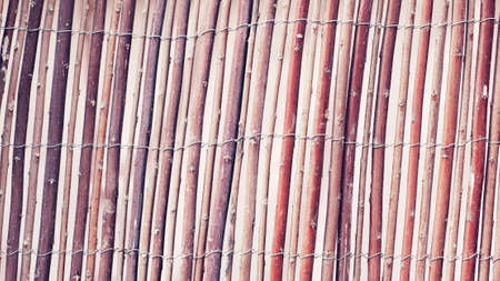 Wattle fence of dry twigs as the background. Traditional rustic fence. Abstract wooden backdrop.の写真素材