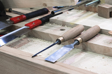 Carpenter wood chisel tool with carving on old weathered wooden workbench