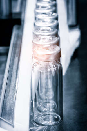 Glass bottles in production in the tray of an automatic liquid dispenser; a line for filling medicines against bacteria and viruses; antibiotics and vaccines.の写真素材