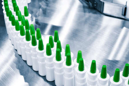 Close-up Many white plastic spray bottles for packaging liquid medicines or cosmetics in a row on a conveyor belt in a pharmaceutical manufacturing factoryの写真素材