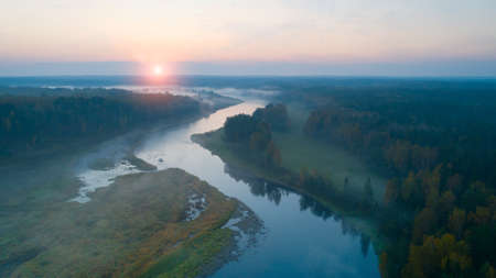 Autumn dawn over foggy forest and river aerial drone viewの写真素材