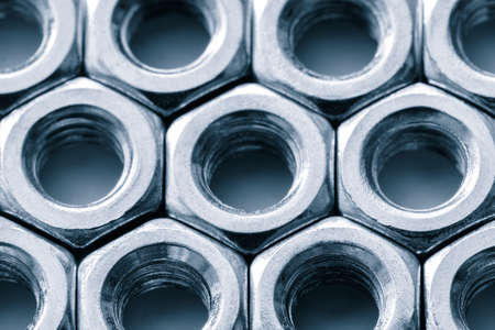 Metal nuts in a row background. Chromed screw nuts. Steel nuts pattern. Tools for work.の写真素材