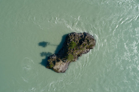 Lonely island in a flowing swift turquoise water stream in a mountain river, aerial summer...