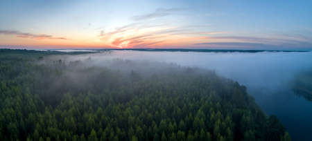 Summer dawn over foggy forest and river aerial drone view. Aerial panoramic landscape with sunset over the river and beautiful clouds on the sky.の写真素材