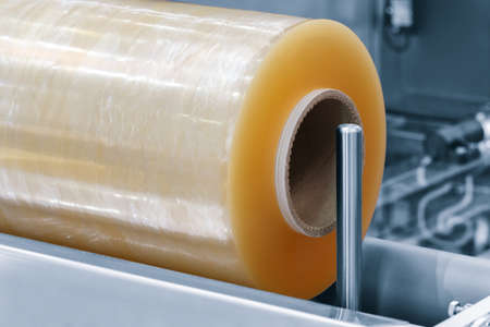 Automatic polyethylene plastic bag production machine with lighting effect. Close-up of the roller of the plastic bag production machine in the light blue scene. product packaging conceptの写真素材