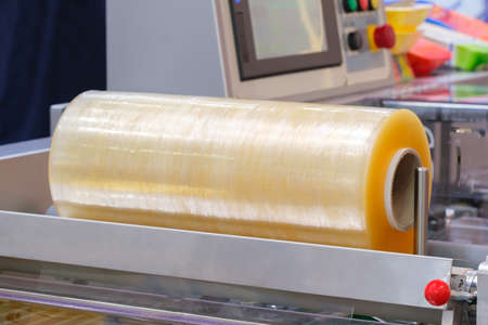 Automatic polyethylene plastic bag production machine with lighting effect. Close-up of the roller of the plastic bag production machine in the light blue scene. product packaging conceptの写真素材