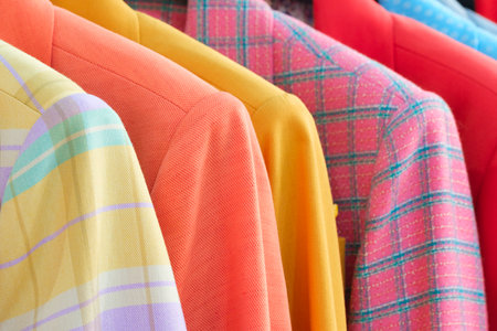 Fashion clothes on clothing rack - bright colorful closet. Closeup of rainbow color choice of trendy female wear on hangers in store closet or spring cleaning concept. summer home wardrobe. women's suits with jacketsの写真素材