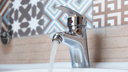 Faucet and water drop close up. Bathroom interior with sink and water tap. Flow water in bathroom with sink.の写真素材