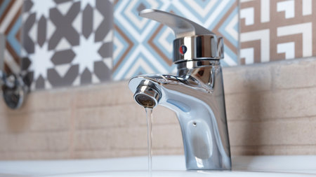 Faucet and water drop close up. Bathroom interior with sink and water tap. Flow water in bathroom with sink.の写真素材