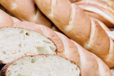 A close up of a loaf of bread with a few slices missing. The bread is white and has a slightly brown...