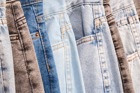 A row of jeans with different colors and patterns. The jeans are hanging on a rackの写真素材