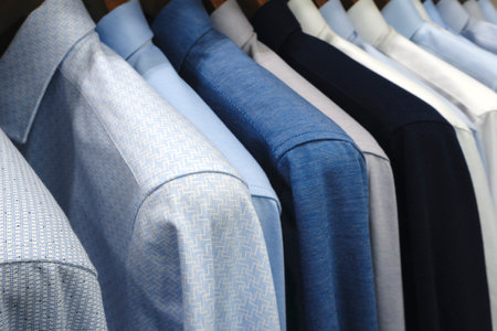 A rack of clothes with a blue shirt on the topの写真素材