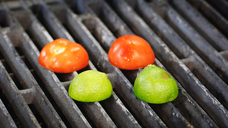Three tomatoes and two limes are on a grillの写真素材