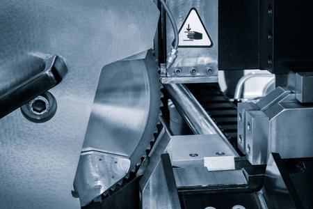 A machine SAW with a warning sign on it. The machine is blue and has a black handleの写真素材