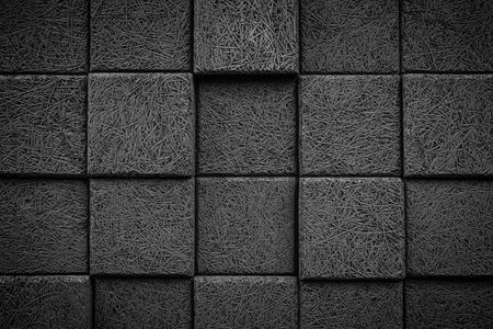 A black and white photo of a wall made of gray blocks. The blocks are arranged in a grid pattern, with some of them slightly overlapping. The photo has a minimalist and modern feel to itの写真素材