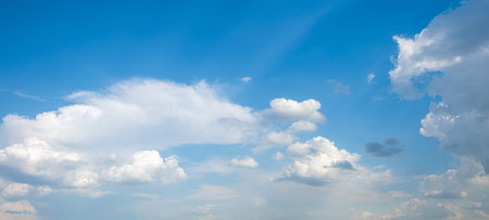 The sky is blue with a few clouds scattered throughout. The clouds are white and fluffy, giving the...