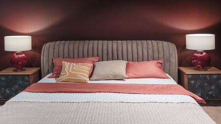 A bed with a red comforter and pillows. The pillows are arranged in a way that creates a sense of comfort and relaxation. The bed is surrounded by a red wall, which adds a warmの写真素材