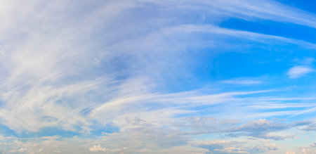 The sky is blue and filled with clouds. The clouds are scattered throughout the sky, with some closer to the ground and others higher upの写真素材