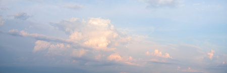 A pink and white cloudless sky with a pinkish hue. The sky is filled with clouds and the sun is...