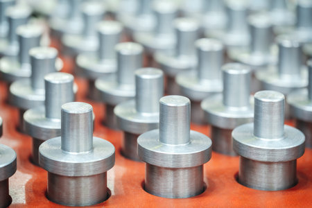 Row of metal cylinders on red background. Cylinders are all the same size and shape, industrial...