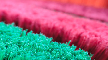 A close up of a green and red brush with a pink stripe. The brush is made of synthetic fibers and is used for cleaningの写真素材