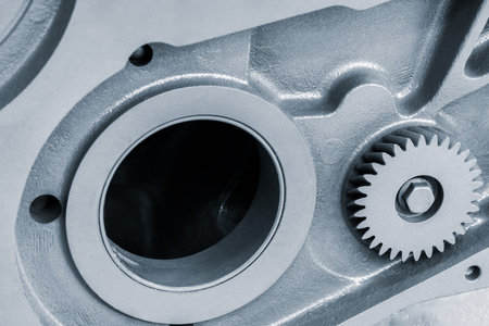 A close up of a gear with a hole in the middle. The gear is silver and has a few small holes around...