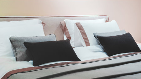 A bed with a white comforter and pillows. The pillows are black and white, and there are two of...