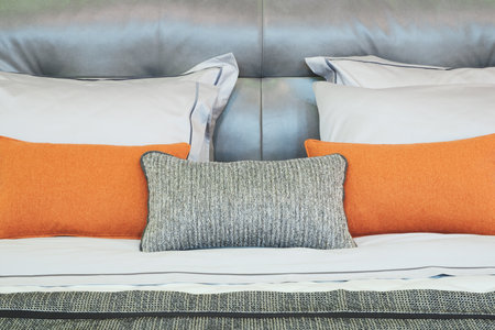 A bed with a gray and orange pillow. The pillow is on the right side of the bedの写真素材