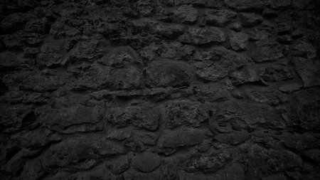 A black stone wall with a lot of rocks. wall is very dark and has a lot of texture backgroundの写真素材
