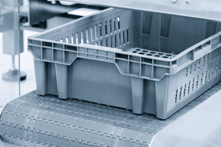 A plastic container is on a conveyor belt. The container is empty