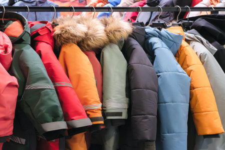 Rack of jackets with a variety of colors and styles. The jackets are hanging on a rack, and they are all different sizes and colorsの写真素材