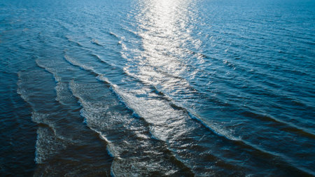 top view of Ocean blue and calm with sun rays reflection on smooth waves as textured blue background...