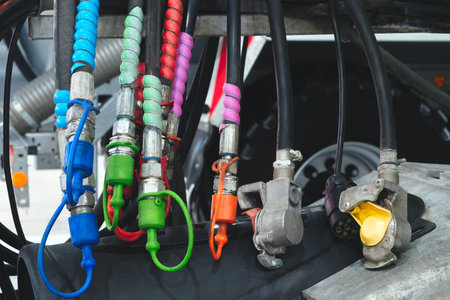 A bunch of colorful rubber hose clamps are hanging from a vehicle. The clamps are in various colors,...