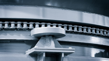 A metal chain is connected to a metal plate. The chain is visible from the side, and it is quite...