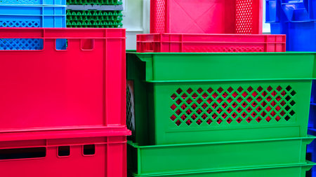 A stack of colorful plastic containers, including green, red, and blue. The containers are piled on...