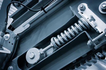 A close up of a machine with a spring inside. The spring is made of metal and is attached to a bolt....
