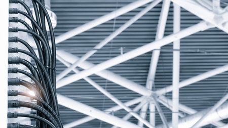 A black wire is hanging from the ceiling. The wire is long and twisted industrial concept background