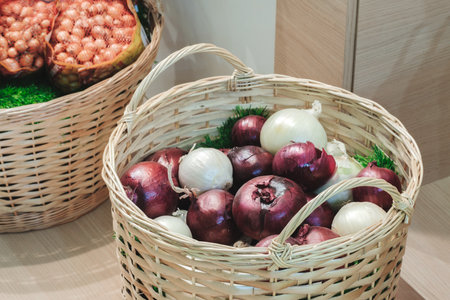 A basket full of onions and a basket of pomegranates are displayed side by side. onions are piled high in the basket, while pomegranates are in the background. Concept of abundance and varietyの写真素材