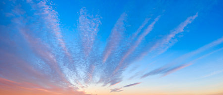 sky is blue with a few clouds. The clouds are white and scattered. The sun is setting and the sky is turning pinkの写真素材