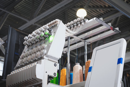 A machine is weaving a fabric with many threads. The machine is in a factory. Concept of industry and productionの写真素材