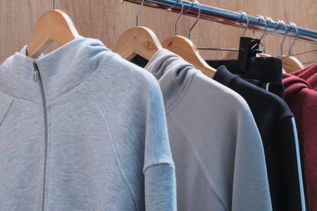 A rack of clothes with a gray hoodie and a black and red hoodie. The gray hoodie is the most visible